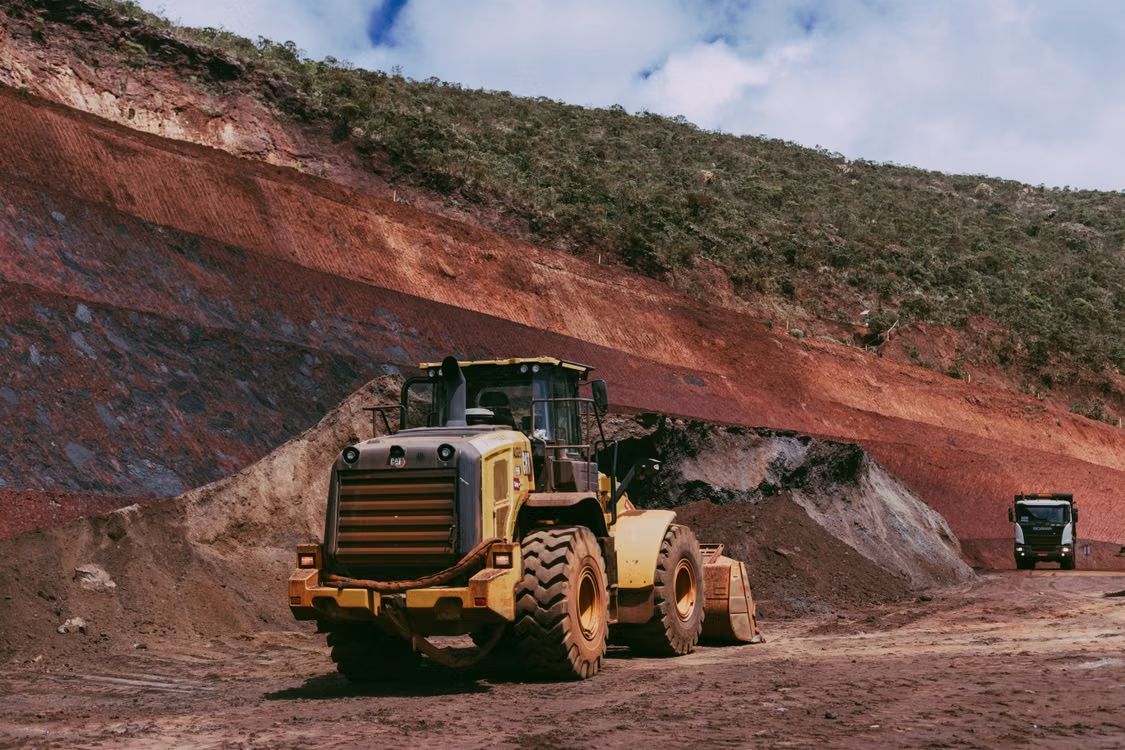 Wheel loader working an iron ore bench, red ore strata visible