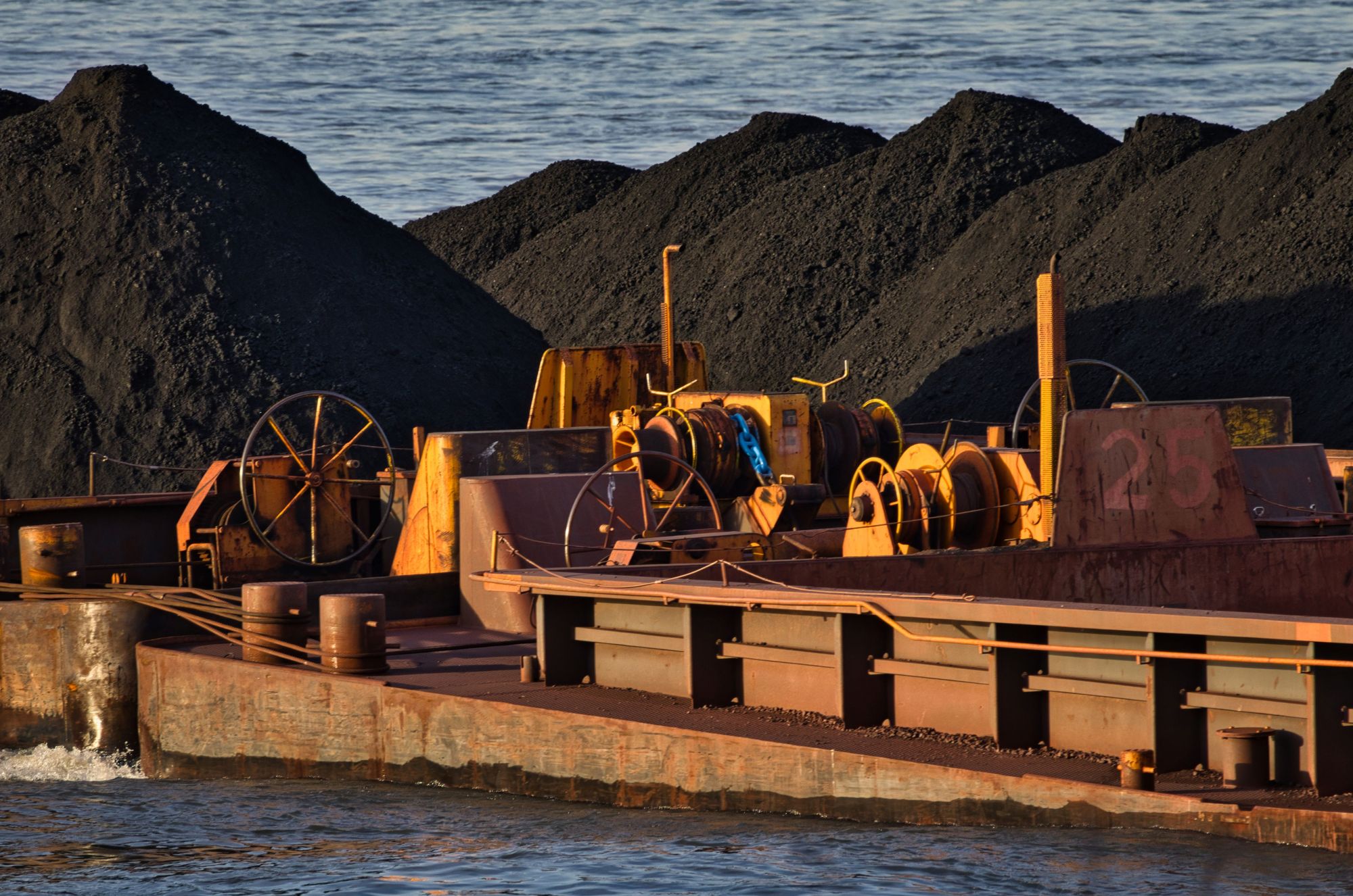 Ore stockpiles and a loaded barge at a bulk export terminal